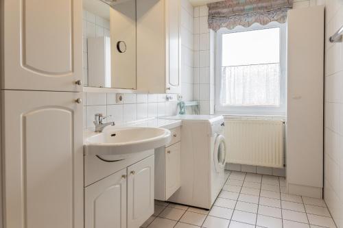 La salle de bains blanche est pourvue d'un lavabo et d'un lave-linge. dans l'établissement 50178..., à Harlesiel