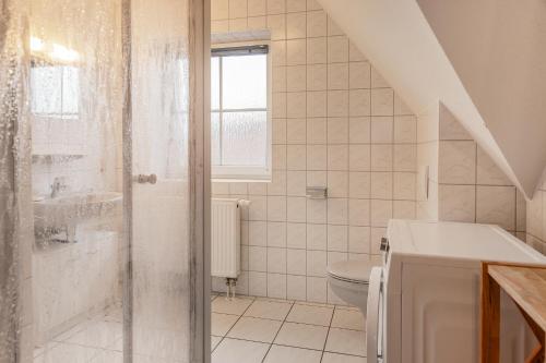 y baño blanco con ducha y aseo. en 50030 Ferienwohnung Nordwind en Carolinensiel