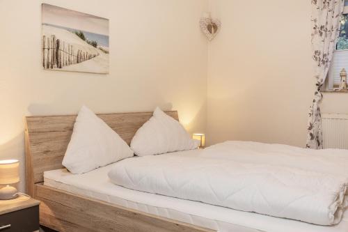 een slaapkamer met een bed met witte lakens en kussens bij 50139 Atlantis in Carolinensiel