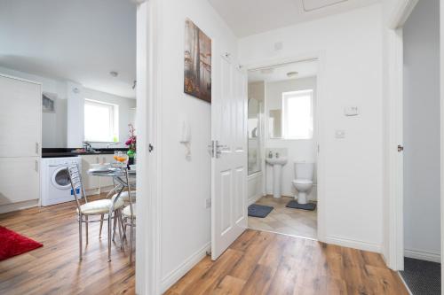 a hallway with a dining room and kitchen with white walls at 2-BR Executive En-Suite Apartment by MBiZ in Coventry