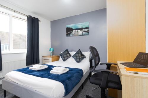 a bedroom with a bed and a desk with a laptop at 2-BR Executive En-Suite Apartment by MBiZ in Coventry