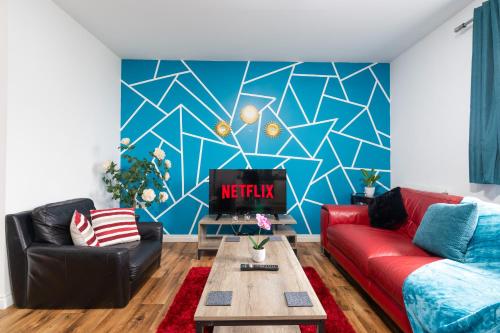 a living room with a red couch and a blue wall at 2-BR Executive En-Suite Apartment by MBiZ in Coventry