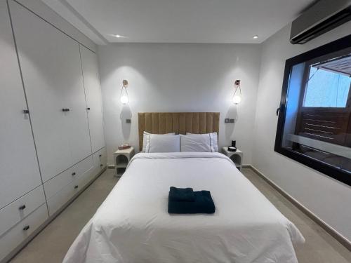 Un dormitorio con una cama blanca con una bolsa azul. en Appartement dans triangle d’or en Marrakech