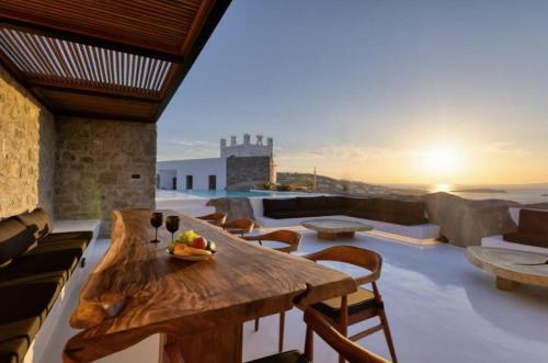une pièce avec une table et des chaises en bois sur un toit dans l'établissement Exquisite Mykonos Villa Villa Apocryphos 6 Bedrooms Unique Aegean Sea View, à Glastros
