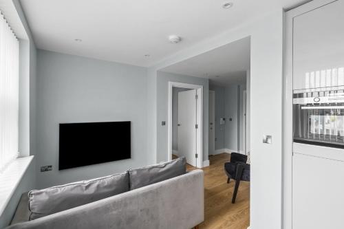 ein Wohnzimmer mit einem Sofa und einem TV an der Wand in der Unterkunft Luxurious One Bedroom Apartment in Bond Street in Chelmsford