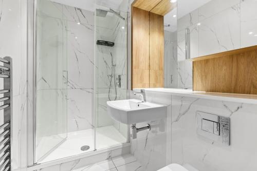 a white bathroom with a shower and a sink at Luxurious One Bedroom Apartment in Bond Street in Chelmsford