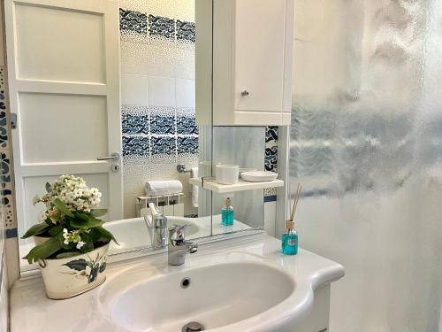 a white bathroom with a sink and a vase of flowers at Ca del Sole - FREE Parking in La Spezia