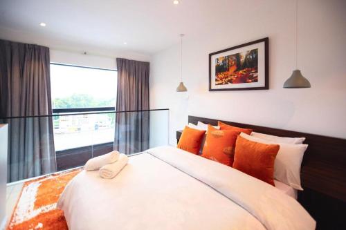 a bedroom with a large white bed with orange pillows at Embassy Gardens Royal Suites Apartments in Accra