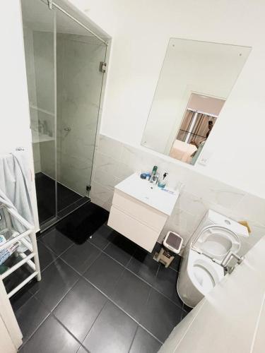 a bathroom with a shower and a toilet and a sink at Embassy Gardens Royal Suites Apartments in Accra