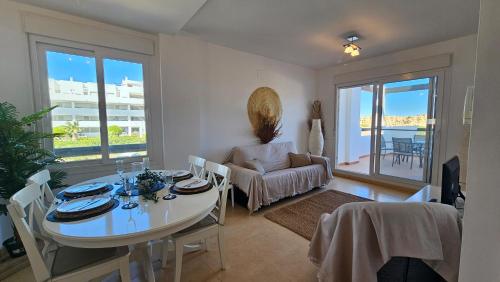 ein Wohnzimmer mit einem Tisch und ein Esszimmer mit Aussicht in der Unterkunft Tranquil sunny apartment las Terrazas de la Torre Golf Resort Spain in Murcia