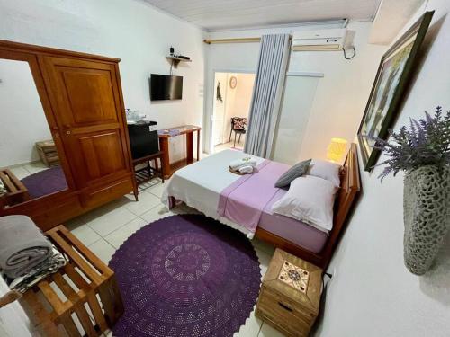 a bedroom with a bed and a purple rug at Suíte Lavanda Cama & Café - Centro, Marechal Floriano-ES in Marechal Floriano