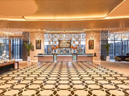 een lobby met een grote kamer met een dambordvloer bij Pullman New Delhi Aerocity- International Airport in New Delhi