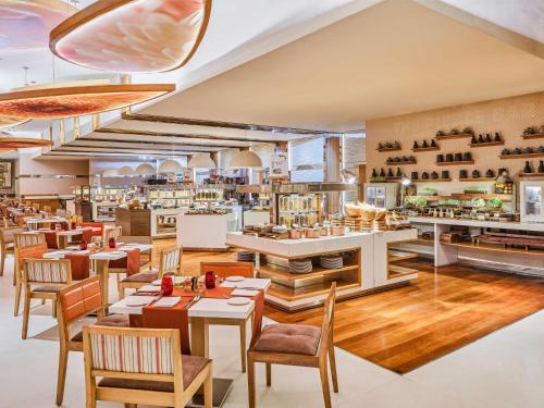 un restaurante con mesas y sillas y una cocina en Pullman New Delhi Aerocity- International Airport en Nueva Delhi