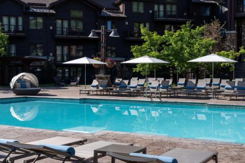 a swimming pool with lounge chairs and umbrellas at Waldorf Astoria Park City in Park City