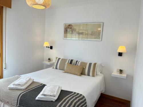 Un dormitorio con una cama blanca con dos toallas encima. en Exclusiva casa en playa América, cerca de Baiona, en Nigrán