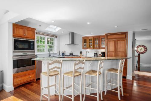 a kitchen with a large white island with bar stools at 14 Hallet Lane Chatham Cape Cod - - Sand Simeon in Chatham