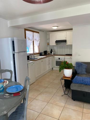 une cuisine avec des armoires blanches, une table et un canapé dans l'établissement Sous la pinède provençale, à La Destrousse