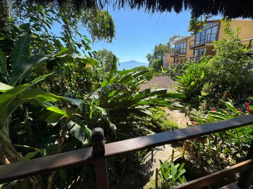 uma vista para um jardim a partir de uma cerca de madeira em Chalé Maria Bonita - Ilha Grande, RJ em Angra dos Reis