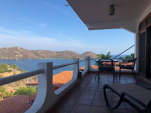 a balcony with tables and chairs and a view of the water at Hermosa vista de la bahía de Zihuatanejo in Zihuatanejo