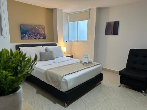 a bedroom with a bed and a black chair at Laureles Guest House LGH Hotel in Medellín