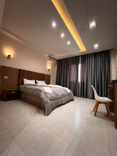 ein Schlafzimmer mit einem Bett und einem Stuhl darin in der Unterkunft Hotel Eloued فندق الوادي in Tiksebt
