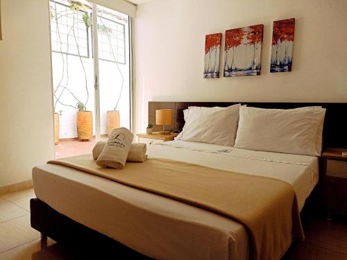 a bedroom with a large bed with two towels on it at Laureles Guest House LGH Hotel in Medellín