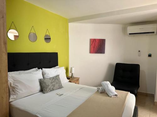 a bedroom with a bed and a black chair at Laureles Guest House LGH Hotel in Medellín