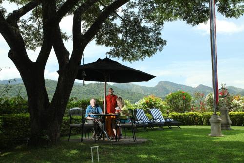 two people sitting at a table under an umbrella at Clingendael Hotel in Digana