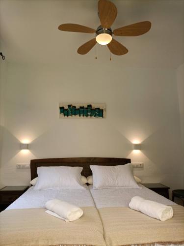 a bed with two pillows and a ceiling fan at El Palomar Rooms Tarifa in Tarifa