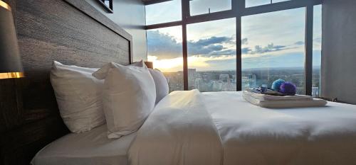 1 cama con almohadas blancas y ventana grande en Serenity - Breathtaking Views, en Nairobi