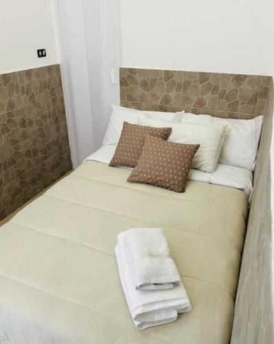 1 cama blanca grande con almohadas y toallas. en Home Ferrari, en Nápoles