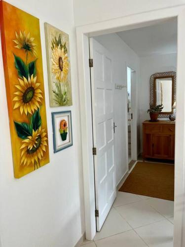 a hallway with two paintings on the wall and a door at Cantinho Ítalo-Germânico Hospedagem - Suíte Girassol - Centro, Marechal Floriano-ES in Marechal Floriano