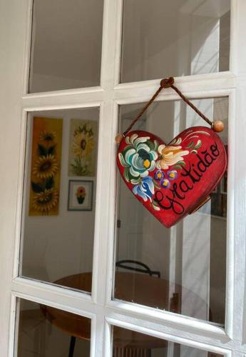 a heart shaped sign hanging on a window at Cantinho Ítalo-Germânico Hospedagem - Suíte Girassol - Centro, Marechal Floriano-ES in Marechal Floriano