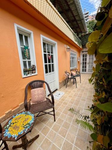 a patio with chairs and a table and a house at Cantinho Ítalo-Germânico Hospedagem - Suíte Girassol - Centro, Marechal Floriano-ES in Marechal Floriano