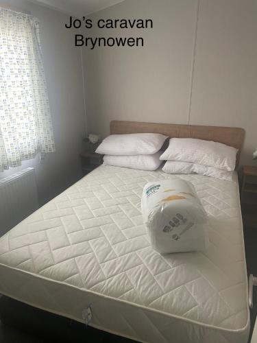 a white bed with a pillow on top of it at Caravan by the beach in Borth