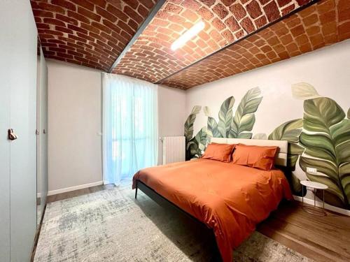 Un dormitorio con una cama naranja con un mural en la pared. en ARTinBòsc by Alterego, en Ferrere