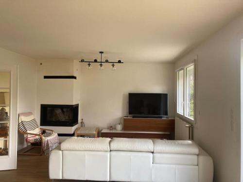 un salon avec un canapé blanc et une télévision dans l'établissement Grande Maison aux portes de Paris JO 2024, à Houilles