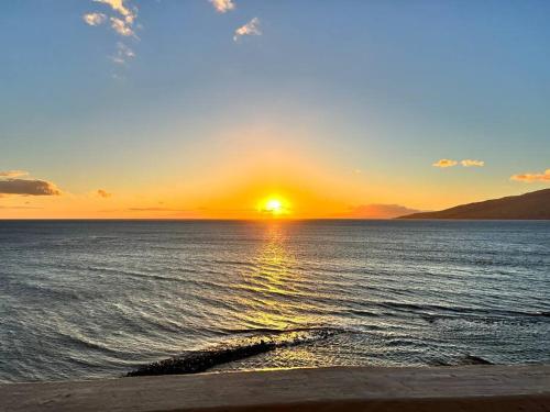 a sunset over the ocean with the sun setting at Beautiful Oceanfront, AC In Each Room, Sleeps 6 in Kihei