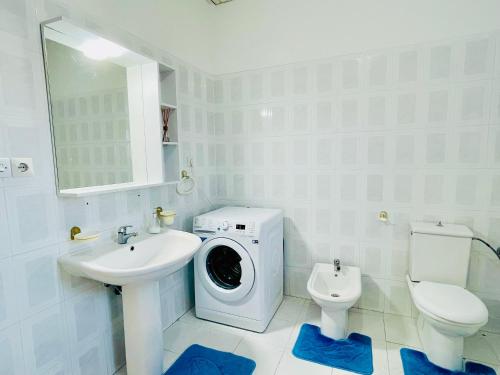uma casa de banho branca com uma máquina de lavar roupa e um lavatório em Mia Guest House - Entire home with balcony & garden em Divjakë