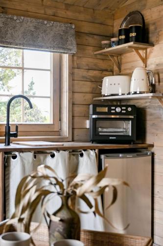 a kitchen with a stove and a microwave at Stylish Tiny Home with Fire Pit in Moss Vale in Moss Vale