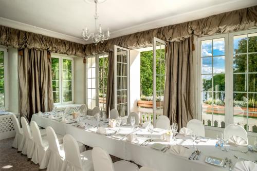 a room with a long table with white chairs and windows at Pałac Zegrzyński in Zegrze