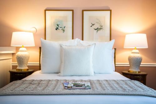 a bedroom with a bed with white pillows and two lamps at Cleftstone Inn in Bar Harbor