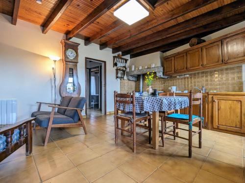 une cuisine avec une table, des chaises et une horloge dans l'établissement Gîte au cœur du village médiéval de Saint-Ilpize - FR-1-582-93, à Saint-Ilpize