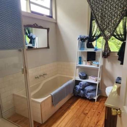 a bathroom with a bath tub and a mirror at Bonnie's by Lake Daylesford in Daylesford
