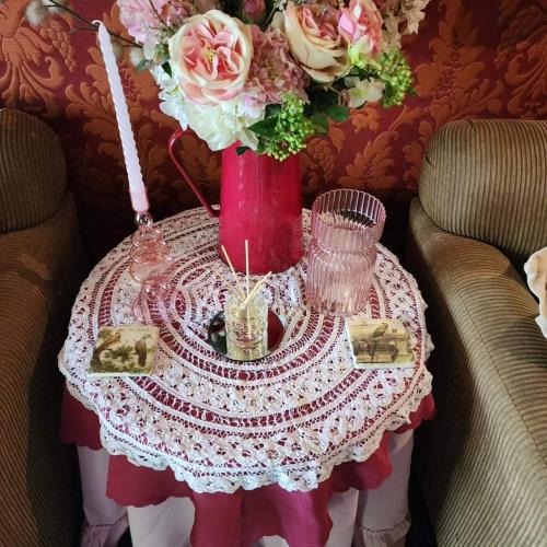 a table with a red vase with flowers on it at Bonnie's by Lake Daylesford in Daylesford