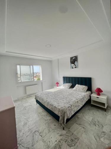 a white bedroom with a bed and a window at Superbe appartement salon deux grandes chambres à coucher in Al Karm