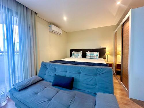 1 dormitorio con 1 cama y 1 sofá azul en Flat Bienal Ibirapuera c/ Sacada UH 1107, en São Paulo