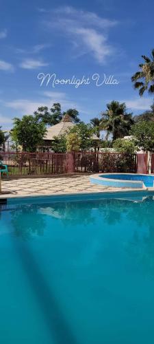 a pool of blue water in front of a fence at مون لايت Moon Light Villa in ‘Ezbet Sa‘dî Mugâwir