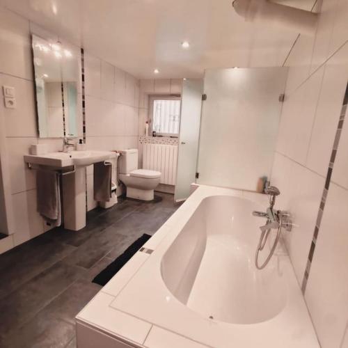 a large white bathroom with a tub and a sink at Maison à 6km de Strasbourg, à 2h de Paris en TGV in Niederhausbergen