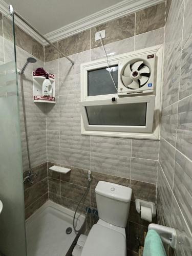 a bathroom with a toilet and a shower and a window at Luxury Inn: 2BR Prime location in Madinaty B12 in Madinaty